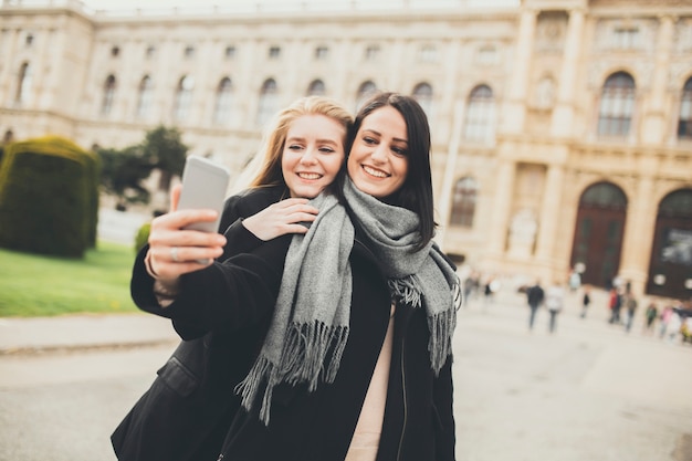 Zwei schöne junge Frauen, die selfie in der Stadt machen