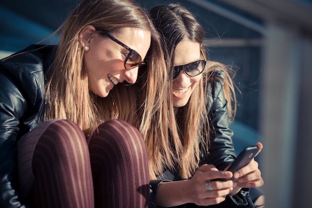 zwei schöne junge Frauen mit Smartphone