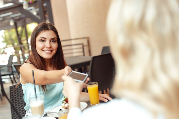 Zwei schöne junge Mädchen sitzen am Tisch im Café