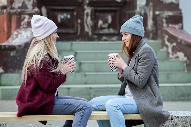 Zwei schöne Mädchen mit langen Haaren trinken Kaffee in der Stadt coffee