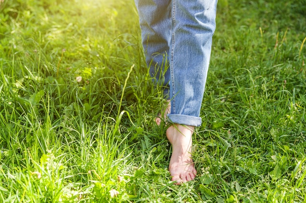 Zwei schöne weibliche Füße, die auf Gras im sonnigen Sommermorgen gehen. Leichter Schritt barfuß Mädchenbeine auf weichem Frühlingsrasen im Garten oder im Park. Entspannungskonzept für gesunde Freiheit.