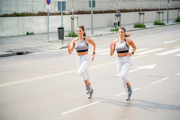 Zwei schöne Zwillingsschwestern laufen in Sportbekleidung durch die Stadt