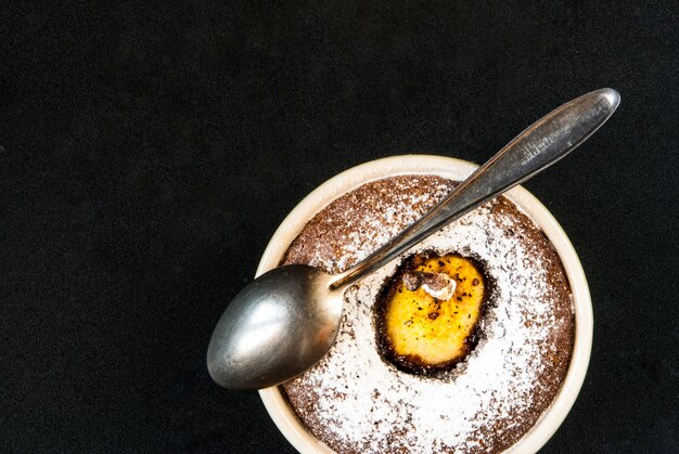 Zwei Schokoladendesserts mit einer Birne auf einem schwarzen Steintisch, Draufsicht