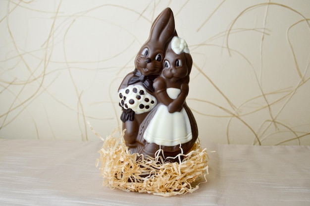 Zwei Schokoladenhasen Zwei schmackhafte, sich umarmende Schokoladenhasen, ein Liebespaar auf hellbeigem Hintergrund