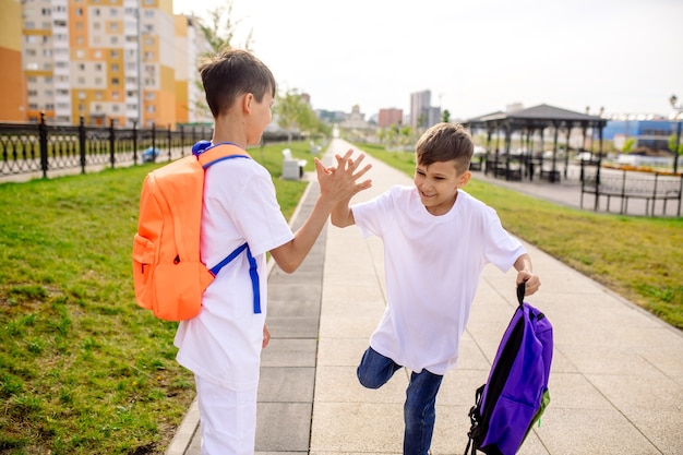 Zwei Schüler gehen mit hellen Rucksäcken zur Schule