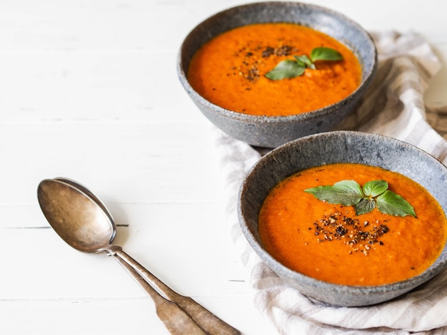 Zwei Schüsseln mit Tomatensuppe mit Gewürzen und frischem Basilikum