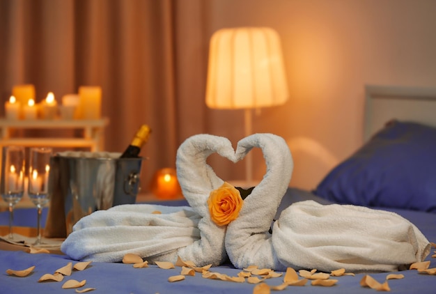 Zwei Schwäne aus Handtüchern und Rosenblättern auf dem Bett im Hotelzimmer Flitterwochen-Konzept