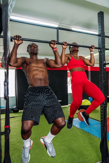 Zwei schwarze Bodybuilder-Athleten in einem Sportstudio machen eine Langhantel-Rückenübung. Konzept zur Stärkung des Körpers im Fitnessstudio