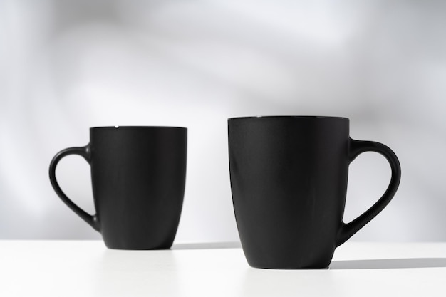 Zwei schwarze Keramikbecher auf grauem Hintergrund mit Schatten