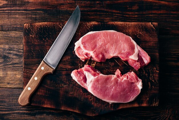 Zwei Schweinelendesteaks mit Messer auf rustikalem Schneidebrett