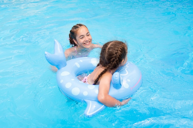 Zwei Schwestermädchen schwimmen in einem Pool mit blauem Wasser und haben einen Fan-Sommer-Familienurlaub