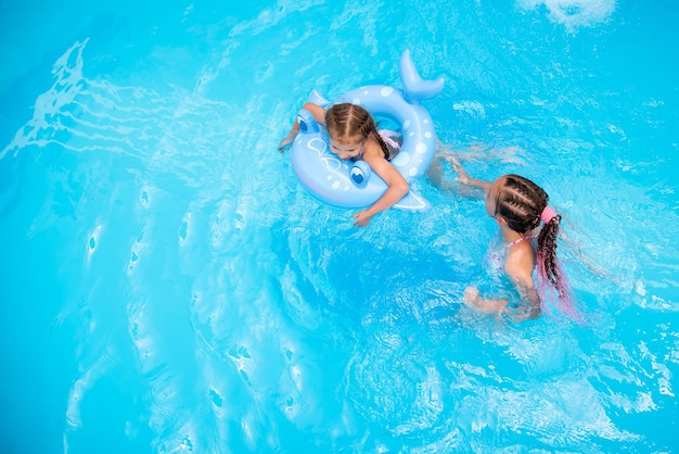 Zwei Schwestermädchen schwimmen in einem Pool mit blauem Wasser und haben einen Fan-Sommer-Familienurlaub