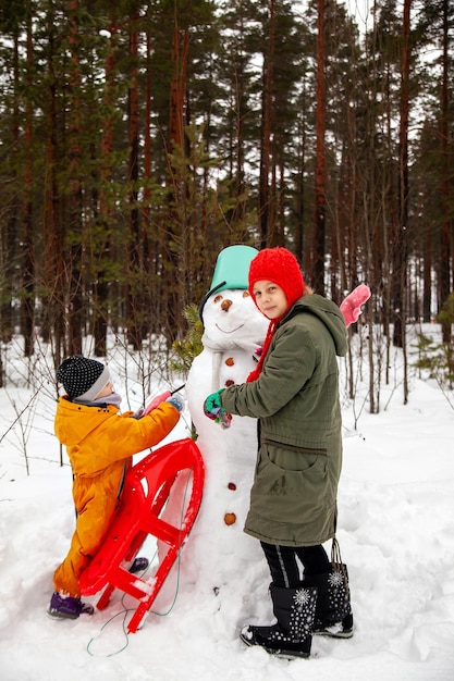 Zwei Schwestern bauen im Winter einen Schneemann