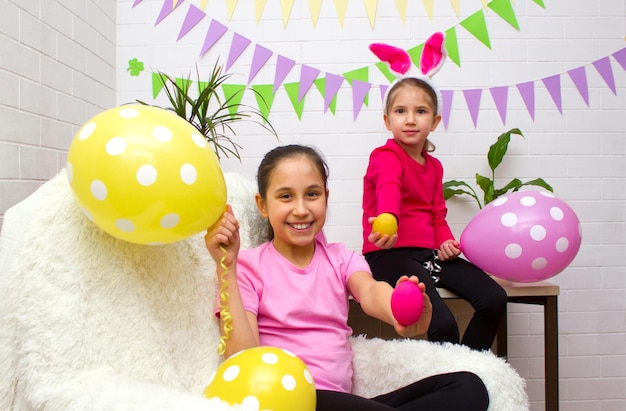 Zwei Schwestern feiern die Osterferien in einem mit Fahnen und Luftballons geschmückten Zimmer