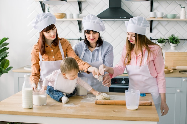 Zwei Schwestern, Großmutter und kleine kleine Tochter, die Feiertagstorte in der Küche zum Muttertag kochen, lässige Lifestyle-Fotoserie im realen Innenraum