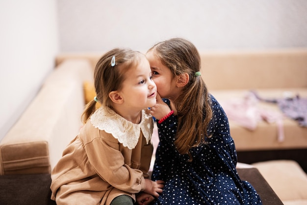 Zwei Schwestern sitzen auf dem Sofa und erzählen und teilen mädchenhafte Geheimnisse miteinander