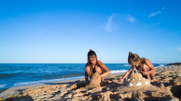 Zwei Schwestern spielen mit Sand an der Seeküste