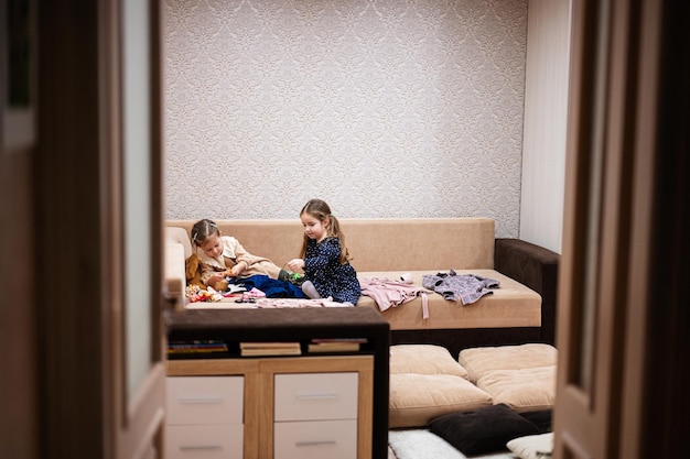 Zwei Schwestern suchen zu Hause auf dem Sofa Kleidung aus dem Kleiderschrank aus