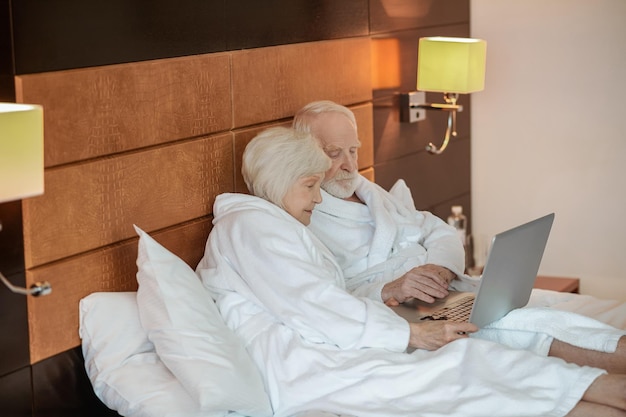 Zwei Senioren schauen sich etwas auf dem Laptop an und sehen interessiert aus