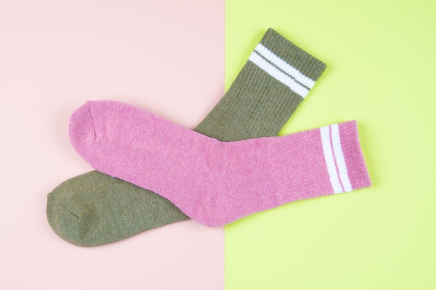 Zwei Socken grün und rosa auf einem mehrfarbigen rosa und grünen Pastellhintergrund mit Kopienraum, Draufsicht. Foto in hoher Qualität