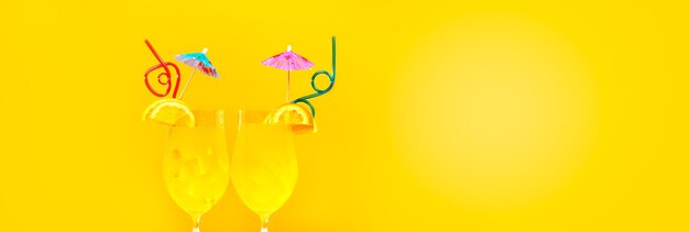 Zwei Sommercocktails mit Strohhalmen auf Gelb