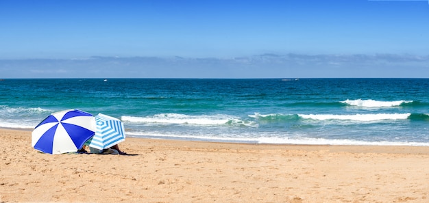 Zwei Sonnenschirme am Strand, blauer Himmel