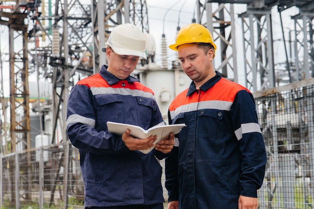 Zwei spezialisierte Umspannwerkingenieure inspizieren moderne Hochspannungsgeräte. Energie. Industrie.