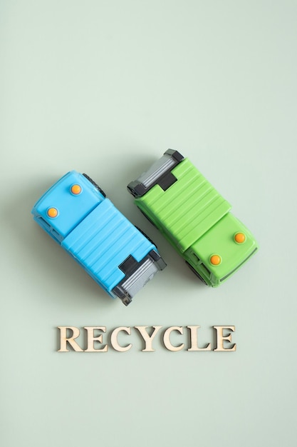 Zwei Spielzeugmüllwagen und recyceln Text auf grünem Hintergrund