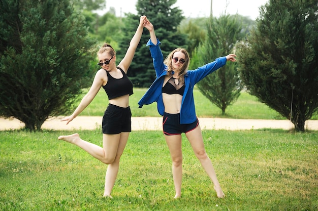 Zwei sportlich schöne Mädchen haben Spaß im Sommer auf einer grünen Wiese im Park