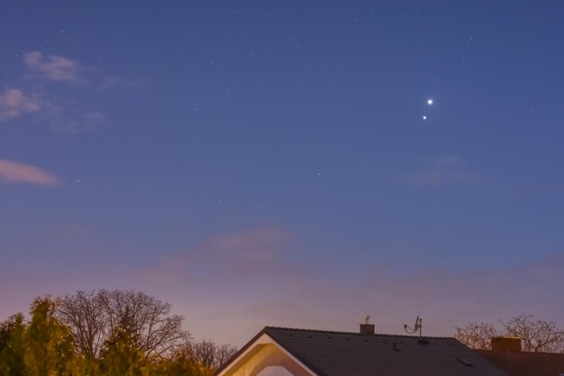 Foto zwei sterne jupiter und venus, die über häuser am himmel leuchten