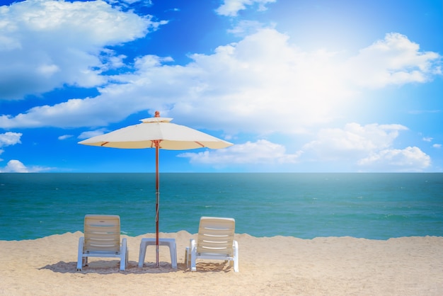 Zwei Strandstühle und weißer Regenschirm mit Hintergrund des blauen Himmels