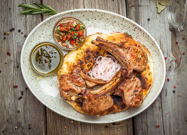 Zwei Stücke gegrilltes Schweinefleisch mit Kräutern auf einem Papier auf einer horizontalen Nahaufnahme der alten Tischoberansicht