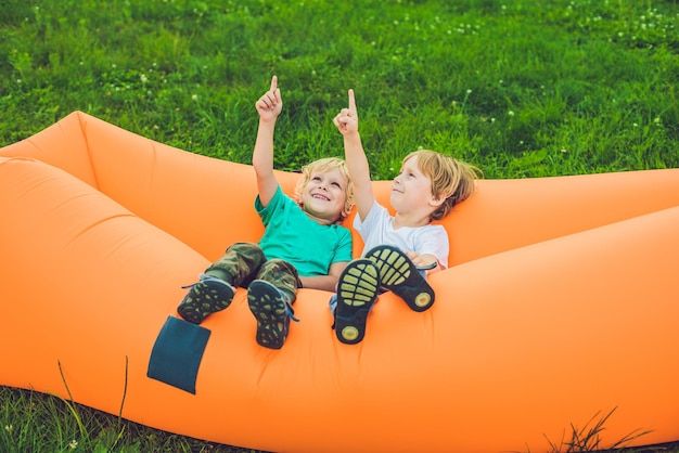 Zwei süße Jungs ruhen auf einem Luftsofa im Park.