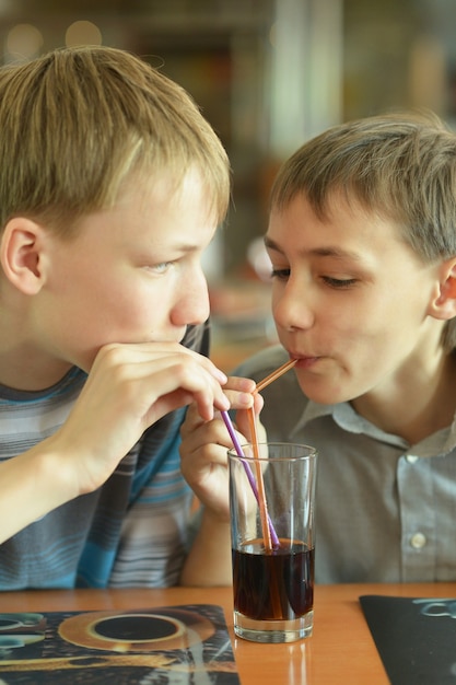 Zwei süße Jungs trinken Cola im Café