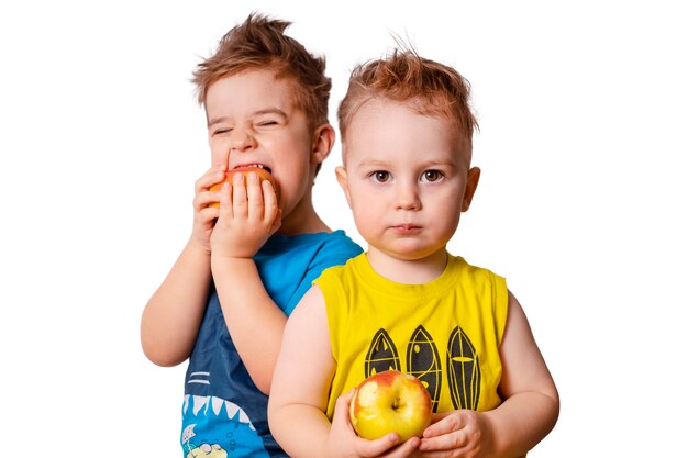 Zwei süße Kinder auf dem weißen Hintergrund, Äpfel essen. Isoliertes Bild.