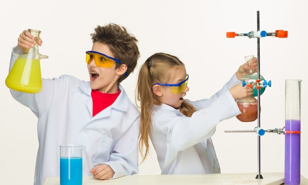 Zwei süße Kinder im Chemieunterricht machen Experimente auf weißem Hintergrund