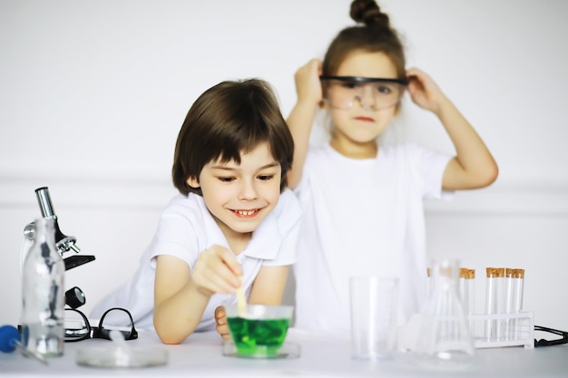 Zwei süße Kinder im Chemieunterricht machen Experimente isoliert auf weißem Hintergrund
