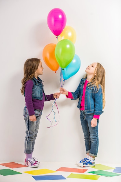 Zwei süße kleine Mädchen mit bunten Luftballons