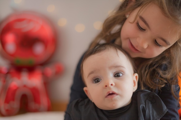 Zwei süße kleine Schwestern warten auf Geschenke vom Weihnachtsmann Weihnachtsdekoration im Hintergrund mit Luftballons und Lichtern