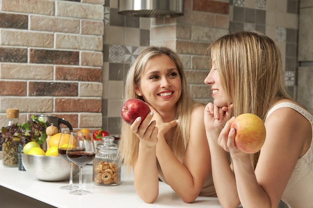 Zwei süße lesbische Frauen trinken Rotwein in der Küche und unterhalten sich süß, während sie sich gegenseitig in die Augen schauen
