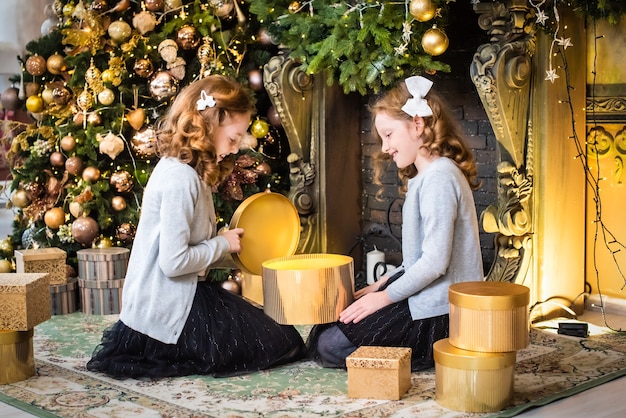 Zwei süße Schwestern öffnen Geschenke am Neujahrsbaum