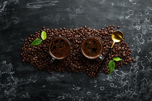 Zwei Tassen duftender Kaffee und Kaffeebohnen auf schwarzem Steinhintergrund Draufsicht Freier Platz für Text