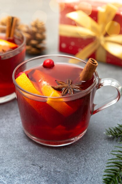 Foto zwei tassen gluhwein mit gewürzen und orangenflecken auf rustikaler tischfläche