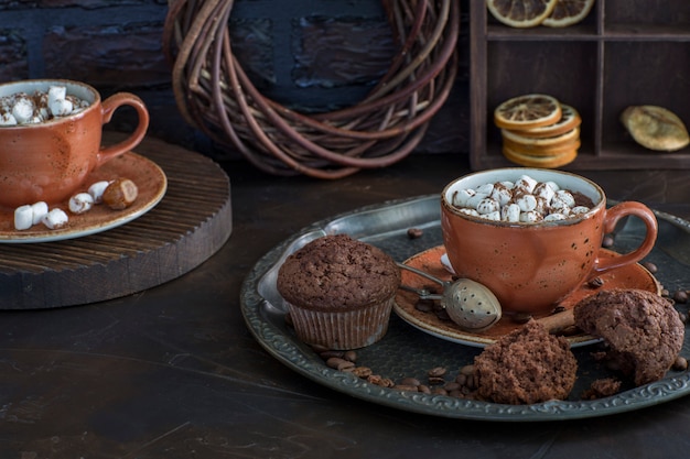 zwei Tassen heiße Schokolade mit Marshmallows und Muffins hautnah