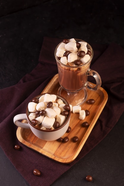 Zwei Tassen heiße Schokolade mit Zimt und Marshmallow auf dunklem Hintergrund