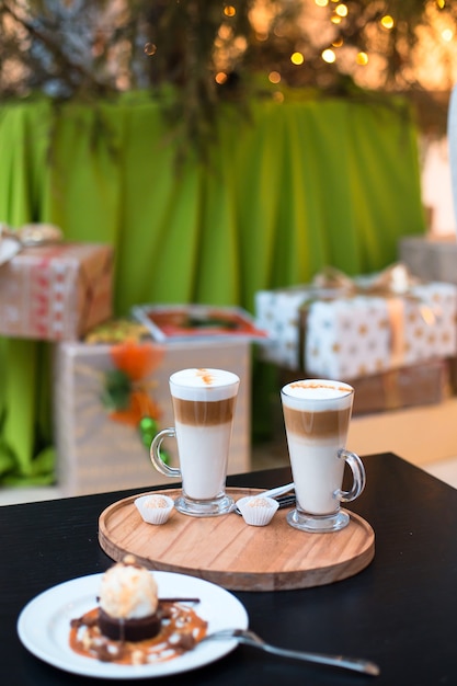 Zwei Tassen Kaffee Latte und Kuchen auf Weihnachtsbaum und Geschenke