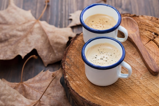 Zwei Tassen Kaffee mit Blättern auf Holz