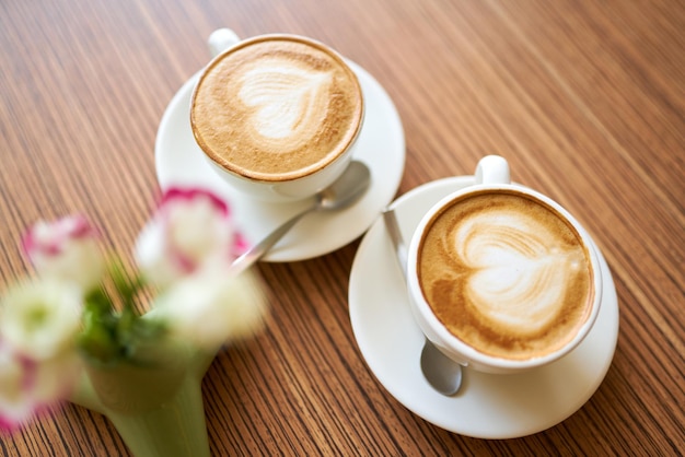 Zwei Tassen Kaffee mit dekorativen Filzherzen, die für den Hochzeitstag an den Griffen gebunden sind