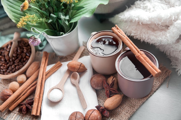 Zwei Tassen Kaffee mit Macadamia-Nüssen und Zimt auf einem Hintergrund von Decken