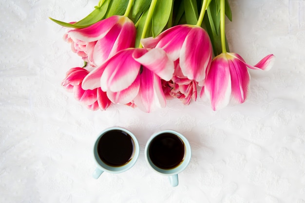 Zwei Tassen Kaffee und ein Strauß rosa Tulpen